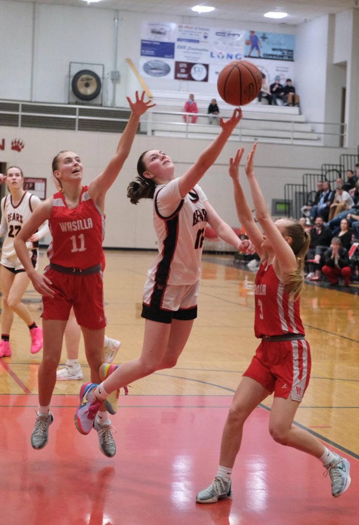 Juneau-Douglas High School: Yadaa.at Kalé junior Gwen Nizich (11) scoops a shot against Wasilla juniors Savannah Kroon (11) and Kinley Lynch (3) during the Crimson Bears 65-34 loss Friday to the Warriors in the George Houston Gymnasium. (Klas Stolpe / Juneau Empire)