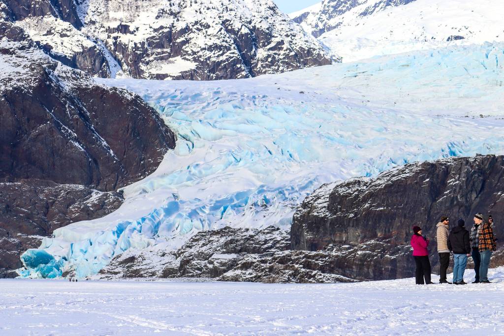 A group of people survey the Mendenhall Glacier from the safety of a trail on Thursday, Feb. 13, 2025. (Jasz Garrett / Juneau Empire)