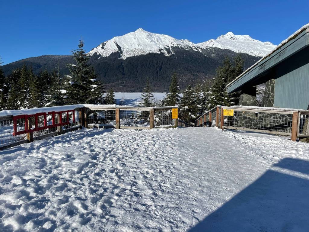 A red ice rescue ladder and yellow ice warning signs are affixed to a fence adjacent to the pavilion on the east side of Mendenhall Glacier on Tuesday, Feb. 11, 2025. During winter, the U.S. Forest Service typically places signs and red ladders at various locations near the lake shore, including Nugget Falls and the west side of the lake. (Laurie Craig / Juneau Empire)