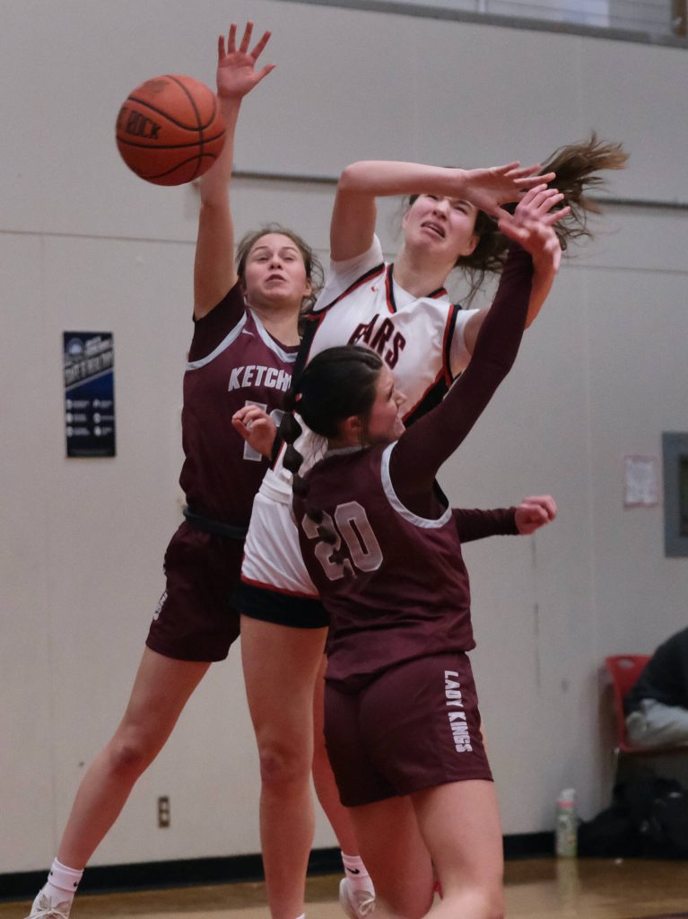 Juneau-Douglas High School: Yadaa.at Kalé senior Cailynn Baxter is fouled while shooting over Ketchikan senior Aspen Bauer (13) and junior Kari Klinger (20) during the Crimson Bears 51-23 win over the Lady Kings on Friday in Juneau. (Klas Stolpe / Juneau Empire)