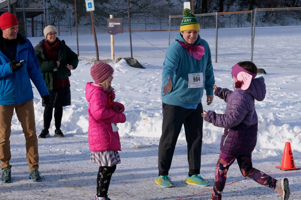 Isabelle Sullivan, right, tags relay partner Clint Sullivan (904) as Maddie Sullivan looks on during the Sweetheart Relay on Saturday at Sandy Beach. (Klas Stolpe / Juneau Empire)