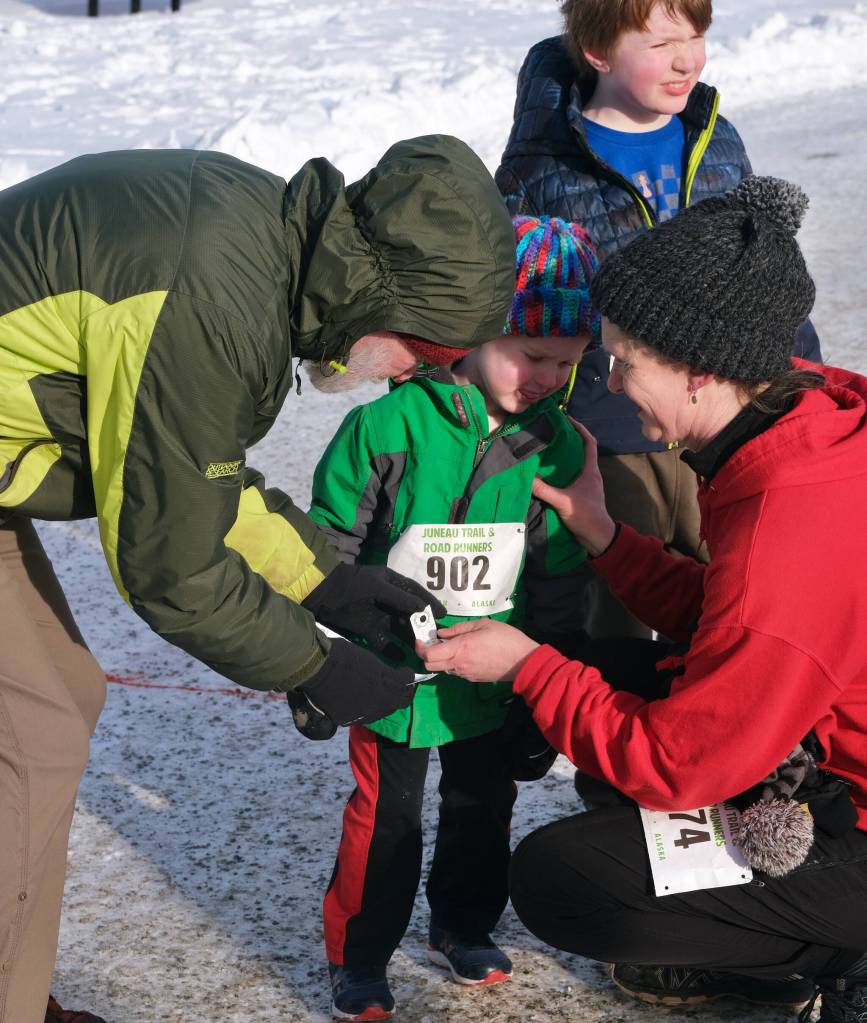 Orion Davis (902) has his bib collected by Paul DeSloover and Faith Davis (974) as he finishes the Sweetheart Relay on Saturday at Sandy Beach. (Klas Stolpe / Juneau Empire)