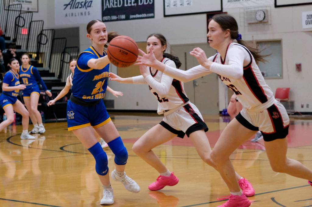 Monroe sophomore Leila Church (21) and Juneau-Douglas High School: Yadaa.at Kalé seniors Kerra Baxter (22) and Cailynn Baxter (23) go for a loose ball during the visiting Rams 52-40 loss to the host Crimson Bears on Friday in the George Houston Gymnasium. (Klas Stolpe / Juneau Empire)