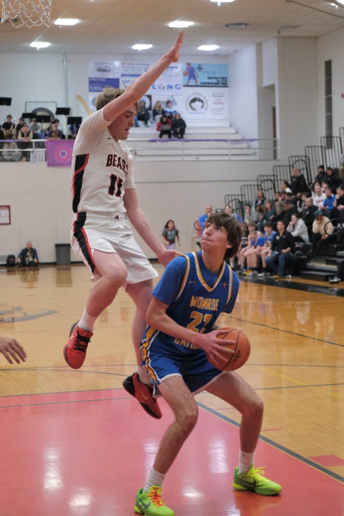 Juneau-Douglas High School: Yadaa.at Kalé senior Ben Sikes (11) defends Monroe senior Tucker Williams (22) during the Crimson Bears 76-55 loss to the Rams on Friday in the George Houston Gymnasium. (Klas Stolpe / Juneau Empire)