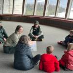 Jude Humphrey, a Student Conservation Association intern for the U.S. Forest Service, reads a story about snowflakes to kids during a Mendenhall Minis event at the Mendenhall Glacier Visitor Center on Saturday morning. (Mark Sabbatini / Juneau Empire)
