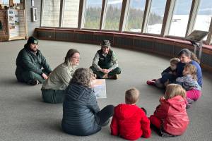 Jude Humphrey, a Student Conservation Association intern for the U.S. Forest Service, reads a story about snowflakes to kids during a Mendenhall Minis event at the Mendenhall Glacier Visitor Center on Saturday morning. (Mark Sabbatini / Juneau Empire)