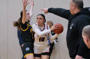 Juneau-Douglas High School: Yadaa.at Kalé senior Addison Wilson (10) is defended by Monroe sophomore Leila Church as Monroe coach Travis Cortez gives directions during the Crimson Bears 40-33 loss to the Rams on Saturday in the George Houston Gymnasium. (Klas Stolpe / Juneau Empire)