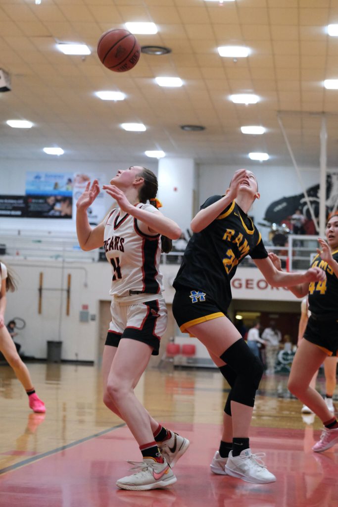Juneau-Douglas High School: Yadaa.at Kalé junior Gwen Nizich (11) and Monroe sophomore Leila Church (21) react to a ball during the Crimson Bears 40-33 loss to the Rams on Saturday in the George Houston Gymnasium. (Klas Stolpe / Juneau Empire)