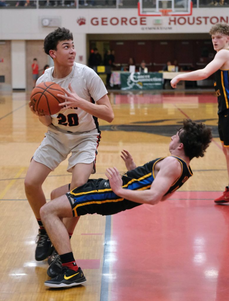 Juneau-Douglas High School: Yadaa.at Kalé junior Elias Dybdahl (20) sets for a shot as Monroe sophomore Adam Geyer attempts to take a charge during the Crimson Bears 71-55 loss to the Rams on Saturday in the George Houston Gymnasium. (Klas Stolpe / Juneau Empire)