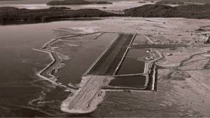Aerial photo of the Juneau airport and newly formed dike around the perimeter in about 1956. Note the absence of any trees and the fully inundated area. (Courtesy Juneau International Airport, photographer unknown).