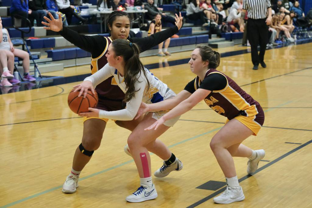 Skagways Lennon Jennings (21) passes around defensive pressure from Hoonahs Nevaeh Campbell (24) and Jora Savland (3) in the Panthers overtime loss to the Braves on Thursday during the 2025 Alaska Airlines Region V 1A Girls Basketball Tournament at Thunder Mountain Middle School. (Klas Stolpe / Juneau Empire)