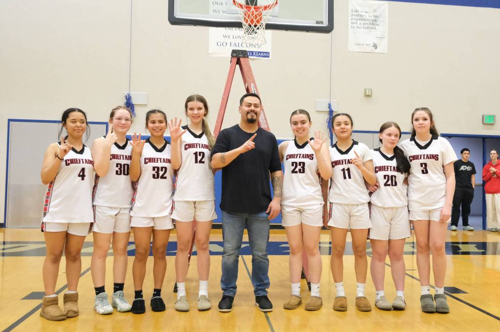 Klawock Chieftains Layla Gregory (4), Alli Demmert (30), Keira Sanderson (32), Kaiya Marvin (12), coach Joseph Sanderson, Lea Armour (23), Jayla Edenshaw (11), Kendra Yates (20) and AnaRose Peratrovich (3) pose after defeating the Hoonah Braves 34-33 for the Region V 1A Girls Basketball Championship on Friday at Thunder Mountain Middle School. (Klas Stolpe / Juneau Empire)