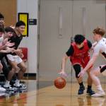 Juneau-Douglas High School: Yadaa.at Kalé senior Gavin Gerrin (3) defends a North Pole player in front of the JDHS bench last weekend. The Crimson Bears boys open the 2A/4A Region V tournament against Kayhi at 7:45 p.m. Thursday in Ketchikan's Clarke Cochran Gymnasium. (Klas Stolpe / Juneau Empire)