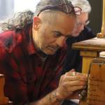 Michael Ruppert, foreground, repairs a fitting in a percussion mechanism for the 1928 Kimball Theatre Pipe Organ in the State Office Building on Tuesday, May 30, 2023. (Mark Sabbatini / Juneau Empire file photo)