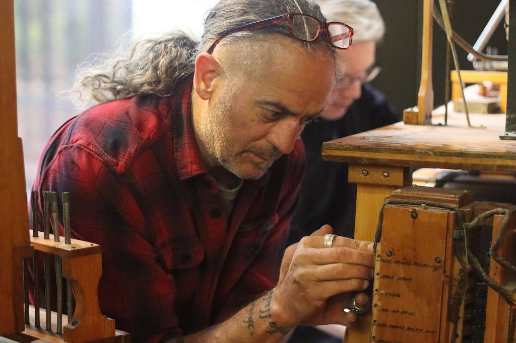 Michael Ruppert, foreground, repairs a fitting in a percussion mechanism for the 1928 Kimball Theatre Pipe Organ in the State Office Building on Tuesday, May 30, 2023. (Mark Sabbatini / Juneau Empire file photo)
