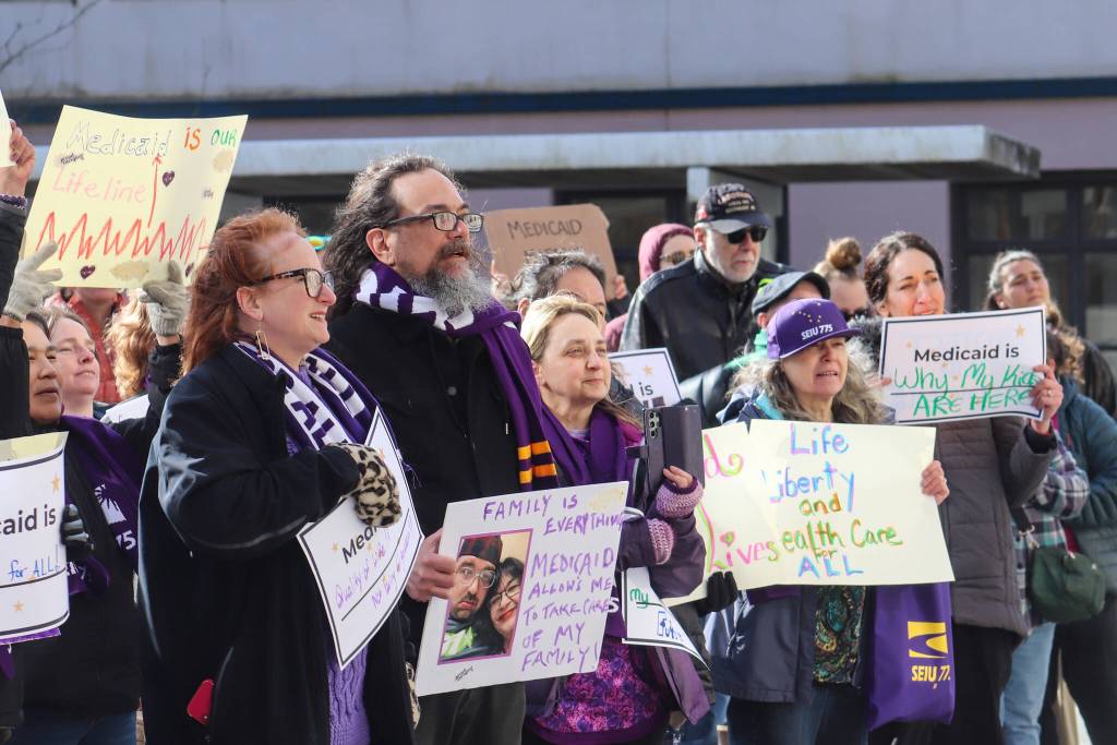 Protesters gather at the Alaska State Capitol on Wednesday, March 12, 2025. Jamie Liston holds a sign that says family is everything. (Jasz Garrett / Juneau Empire)