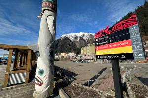 A totem pole and visitor guide sign on the downtown Juneau cruise ship dock on Thursday. (Mark Sabbatini / Juneau Empire)