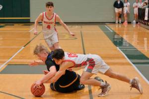 Wrangell senior Lucas Schneider (15) fights for a loose ball with Susitna Valleys Earl Davidson during the Wolves 53-50 loss to the Rams in the 4th/6th-place game Saturday at the 2025 ASAA March Madness Alaska 2A State Basketball Championships at UAAs Avis Sports Center. (Klas Stolpe / Juneau Empire)