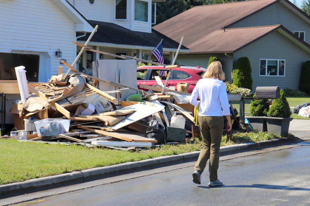 U.S. Sen. Lisa Murkowski (R-Alaska) walks past a home on Killewich Drive with damaged items left outside in the sun on Aug. 7, 2024. (Jasz Garrett / Juneau Empire file photo)