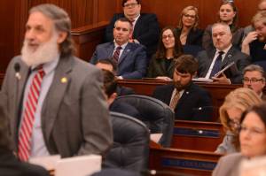 John Boyle, commissioner of the Alaska Department of Natural Resources (center left), sits with staff in the gallery of the Alaska House of Representatives as lawmakers debate the creation of a separate Alaska Department of Agriculture on Wednesday, March 19, 2025. Speaking is Rep. George Rauscher, R-Sutton. (James Brooks/Alaska Beacon)