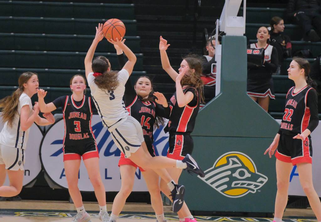 JDHS junior Cambry Lockhart (3), sophomore Layla Tokuoka and seniors Cailynn Baxter (23) and Kerra Baxter (22) defend Mountain City Christian Academys Morgan Maldonaldo (3) during the Crimson Bears 57-37 loss to the Lions in the 3rd/5th-place game Saturday at 2025 ASAA March Madness Alaska 4A Basketball State Championships in Anchorages Alaska Airlines Center. (Klas Stolpe / Juneau Empire)