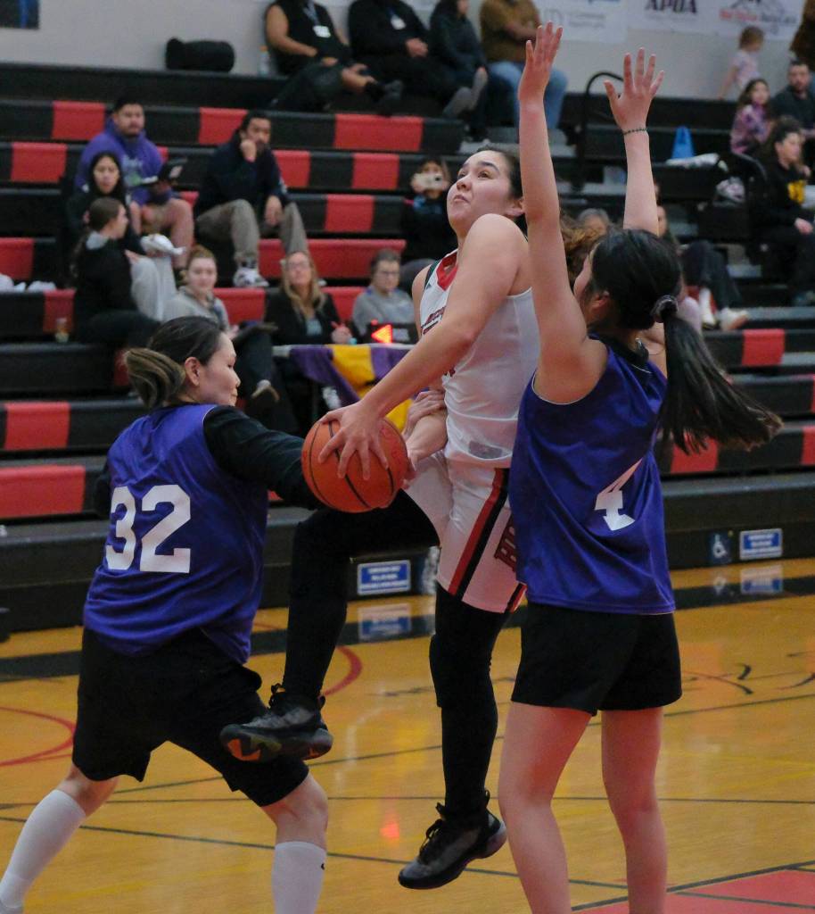 Hoonahs Melissa Fisher is fouled on a shot against Hooper Bays Sandra Lake (32) and Mary Long (4) during Womens Bracket action Monday at the 76th Annual Juneau Lions Club Gold Medal Basketball Tournament in Juneau-Douglas High School: Yadaa.at Kalés George Houston Gymnasium. (Klas Stolpe / Juneau Empire)