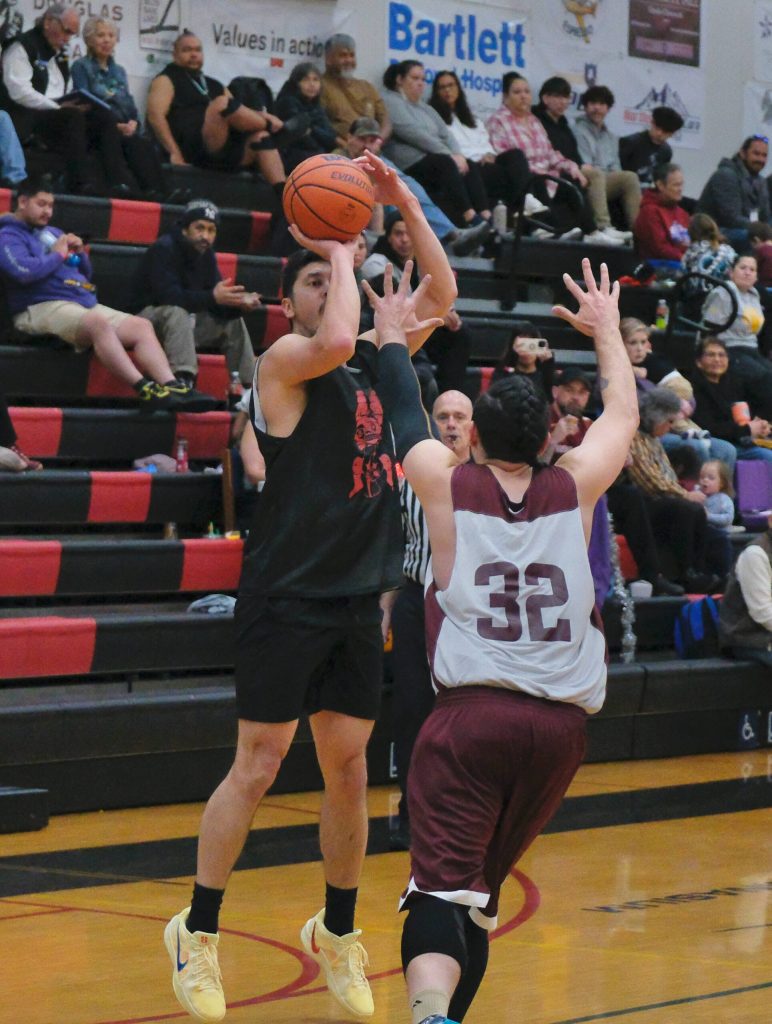 Hydaburgs Darren Edenshaw lines up a three-point shot over Klukwans Cody Hotch (32) during C Bracket action Monday at the 76th Annual Juneau Lions Club Gold Medal Basketball Tournament in Juneau-Douglas High School: Yadaa.at Kalés George Houston Gymnasium. (Klas Stolpe / Juneau Empire)