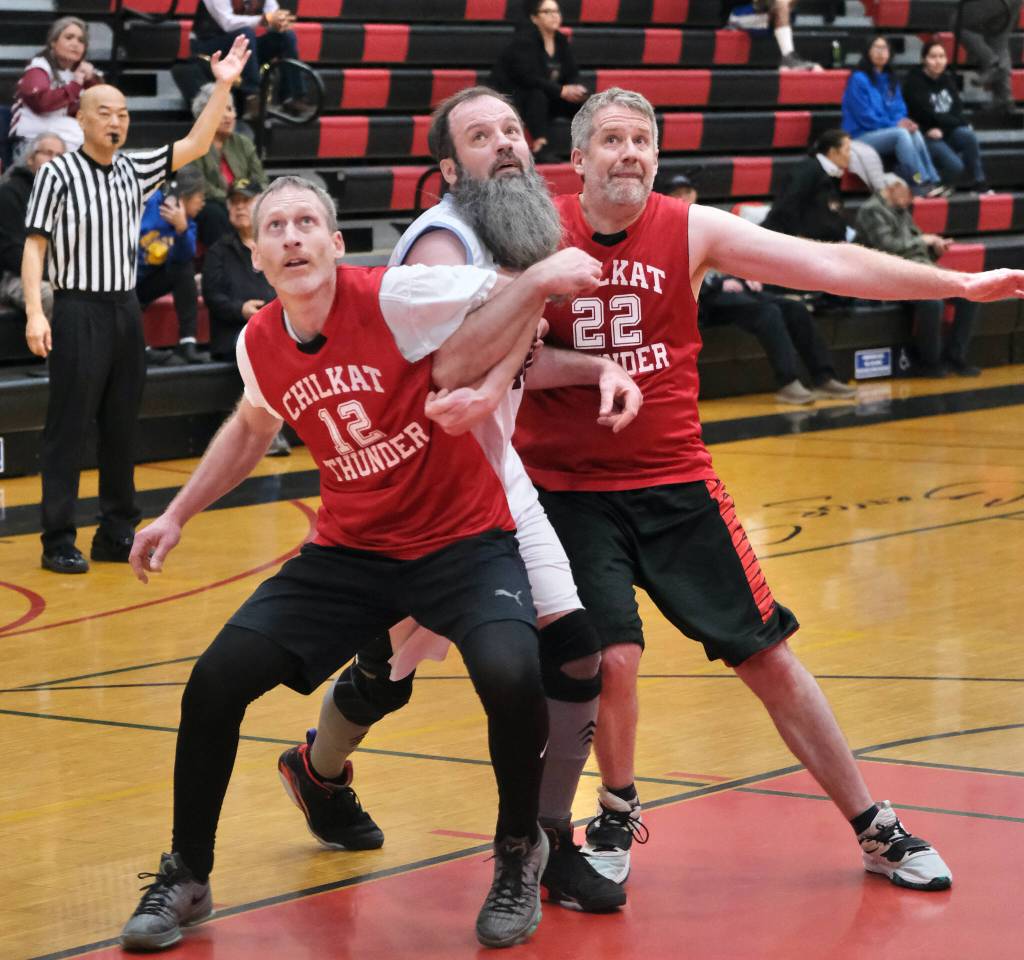 Klukwans Andrew Friske (12) and Dave Buss (22) try to contain Hoonahs Mark Prpich during Klukwans 94-73 Masters Bracket elimination game win Wednesday at the 76th Annual Juneau Lions Club Gold Medal Basketball Tournament in Juneau-Douglas High School: Yadaa.at Kalés George Houston Gymnasium. (Klas Stolpe / Juneau Empire)