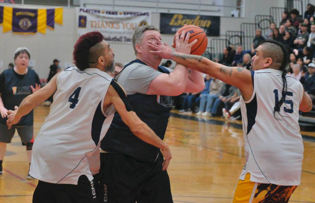 Metlakatlas Danny Marsden is defended by Angoons Marti Fred (4) and Byron Jack Jr. (15) during Metlakatlas 76-60 Masters Bracket elimination game win Wednesday at the 76th Annual Juneau Lions Club Gold Medal Basketball Tournament in Juneau-Douglas High School: Yadaa.at Kalés George Houston Gymnasium. (Klas Stolpe / Juneau Empire)