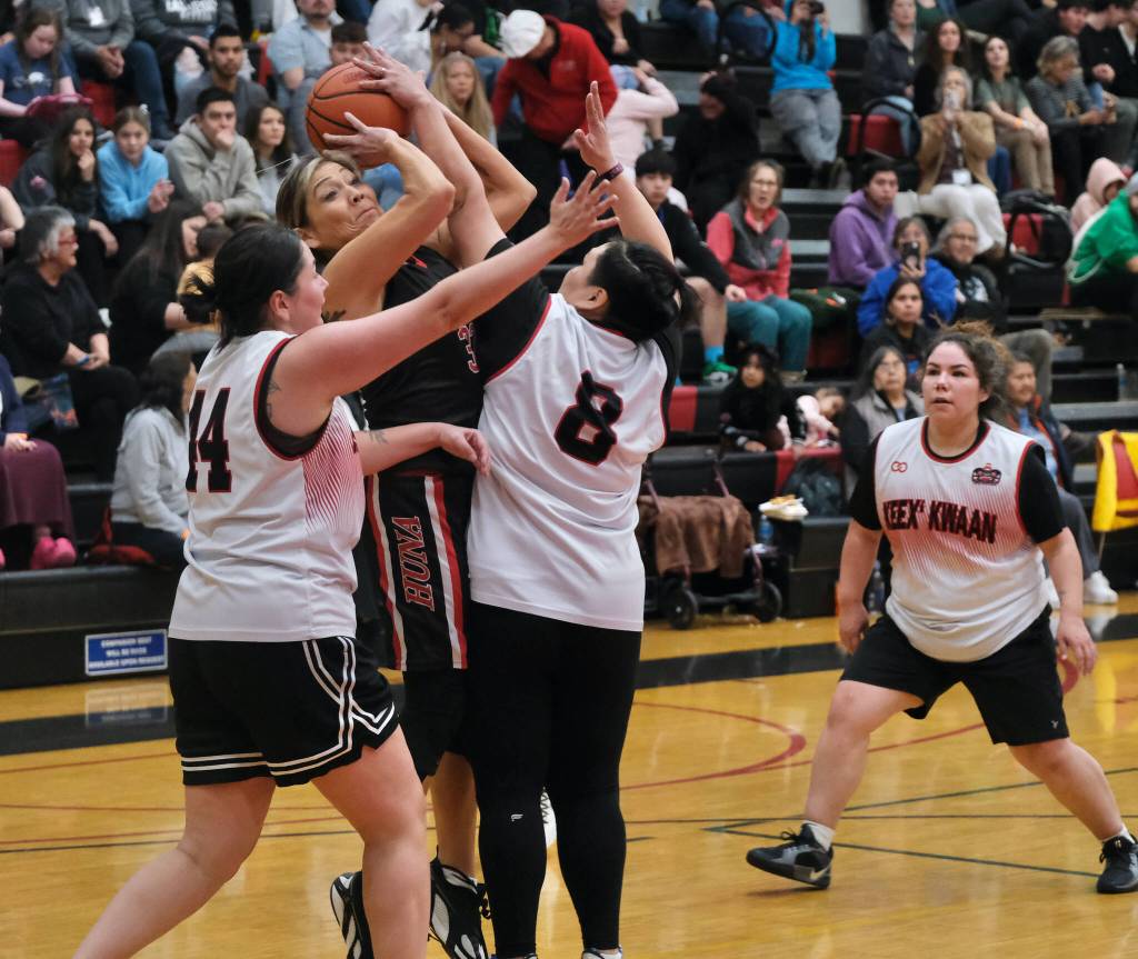 Hoonahs Krissy Bean has her shot checked by Kakes Heather Gatti (44) and Crystal Shaquanie (8) during Hoonahs 60-41 Womens Bracket elimination game win Wednesday at the 76th Annual Juneau Lions Club Gold Medal Basketball Tournament in Juneau-Douglas High School: Yadaa.at Kalés George Houston Gymnasium. (Klas Stolpe / Juneau Empire)