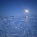Two fat-tire bike riders on a 1,000-mile journey navigate the Topkok Hills east of Nome under the light of the moon. (Photo by Peter Delamere)