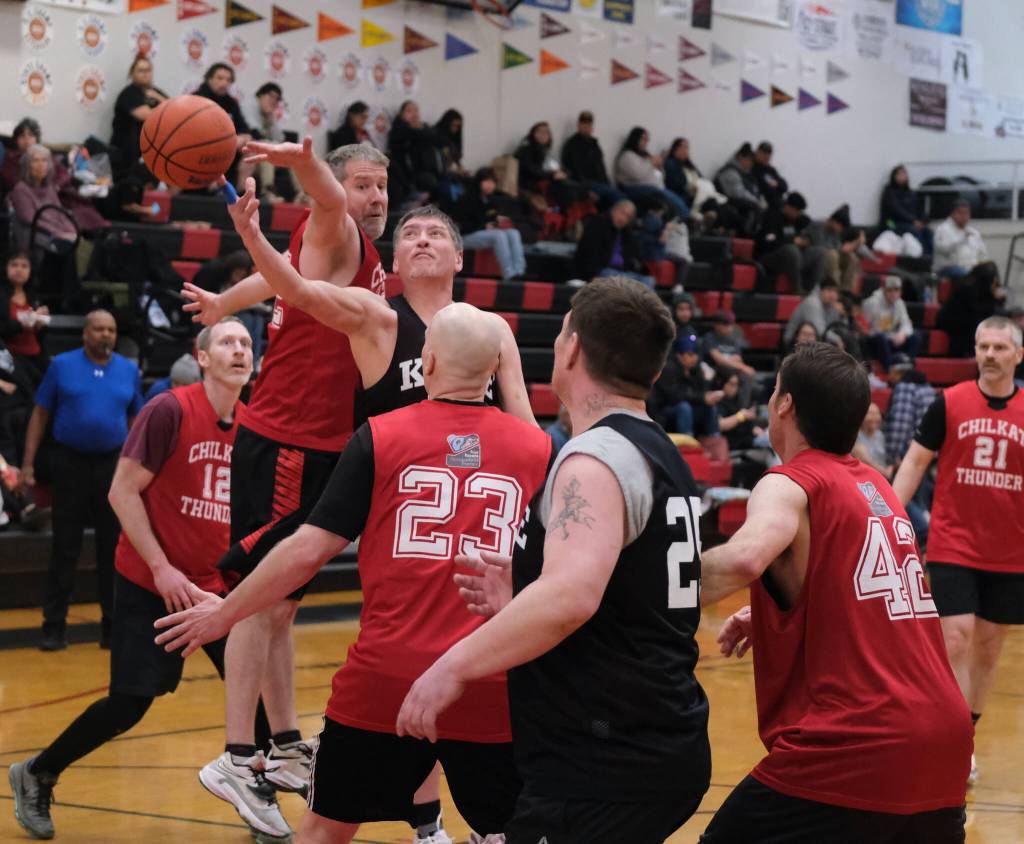 Kakes Lloyd Davis scoops a shot under pressure from Klukwans Dave Buss and Brian Friske (23) during Klukwans 75-43 Masters Bracket elimination game win over Kake at the 76th Annual Juneau Lions Club Gold Medal Basketball Tournament in Juneau-Douglas High School: Yadaa.at Kalés George Houston Gymnasium. (Klas Stolpe / Juneau Empire)