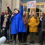 Collette Costa leads the crowd in a closing song during an hour-long protest against the Trump administration in front of the Alaska State Capitol on Saturday. (Mark Sabbatini / Juneau Empire)