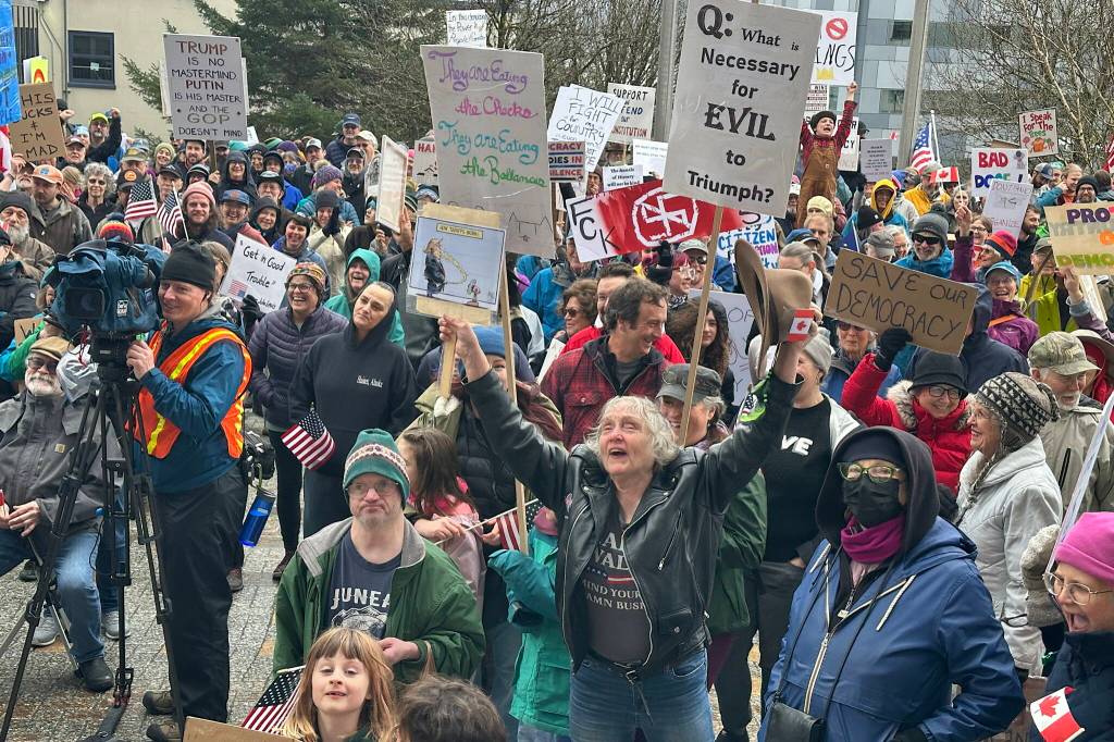 People holding signs and wearing emblems expressing opposition to a wide range of Trump administration actions  including confrontational acts involving Canada, mass firings of federal workers that have largely been found illegal by courts and deportations of people in the U.S. legally  gather in front of the Alaska State Capitol on Saturday. (Mark Sabbatini / Juneau Empire)