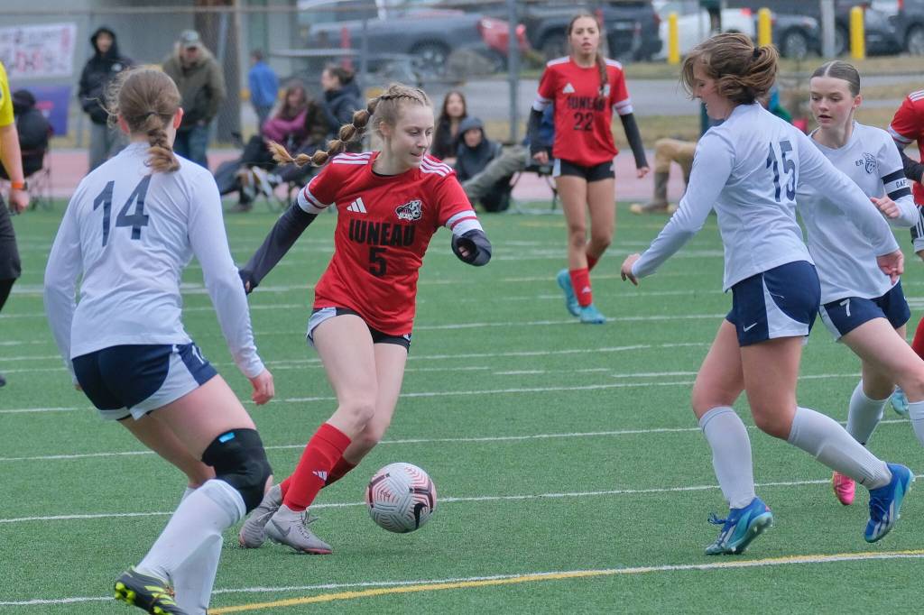 Juneau-Douglas High School: Yadaa.at Kalé junior Peyton Wheeler (5) moves a ball past Eagler Rivers Katherine Christy (14), Addison Goggins (15) and Madeline Rancourt (7) during the Crimson Bears 5-0 win over the Wolves on Saturday at Adair Kennedy Field. (Klas Stolpe / Juneau Empire)