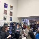 Posters from past Alaska Folk Festivals hang on a wall as people line outside a gift shop for festival items during the opening day of the 50th annual festival Monday at Centennial Hall. (Mark Sabbatini / Juneau Empire)