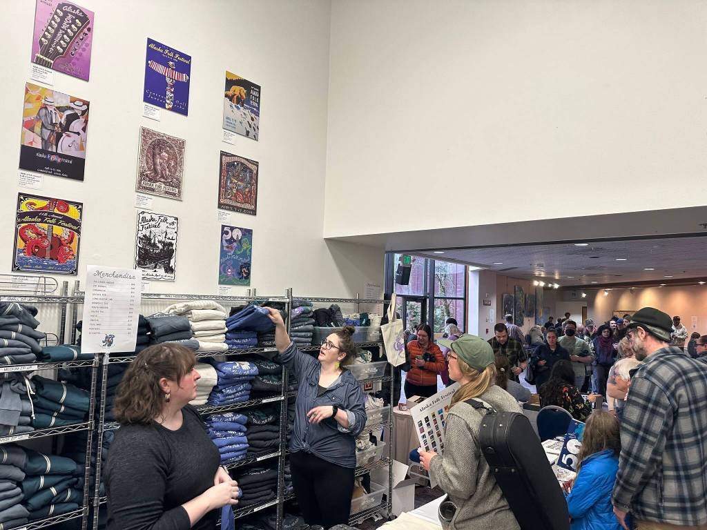 Posters from past Alaska Folk Festivals hang on a wall as people line outside a gift shop for festival items during the opening day of the 50th annual festival Monday at Centennial Hall. (Mark Sabbatini / Juneau Empire)