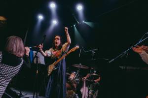 Lucy Nieboer brings an audience member to the stage at the Crystal Saloon in Juneau Tuesday night for an imrpomptu speech about the Haines Pool. That was during the set of relevantly-named Keep the Pool Open (Will Steinfeld/Chilkat Valley News)