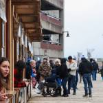Employees of tour operator companies in downtown Juneau await visitors in the rain on Monday, April 14, 2025. (Jasz Garrett / Juneau Empire)