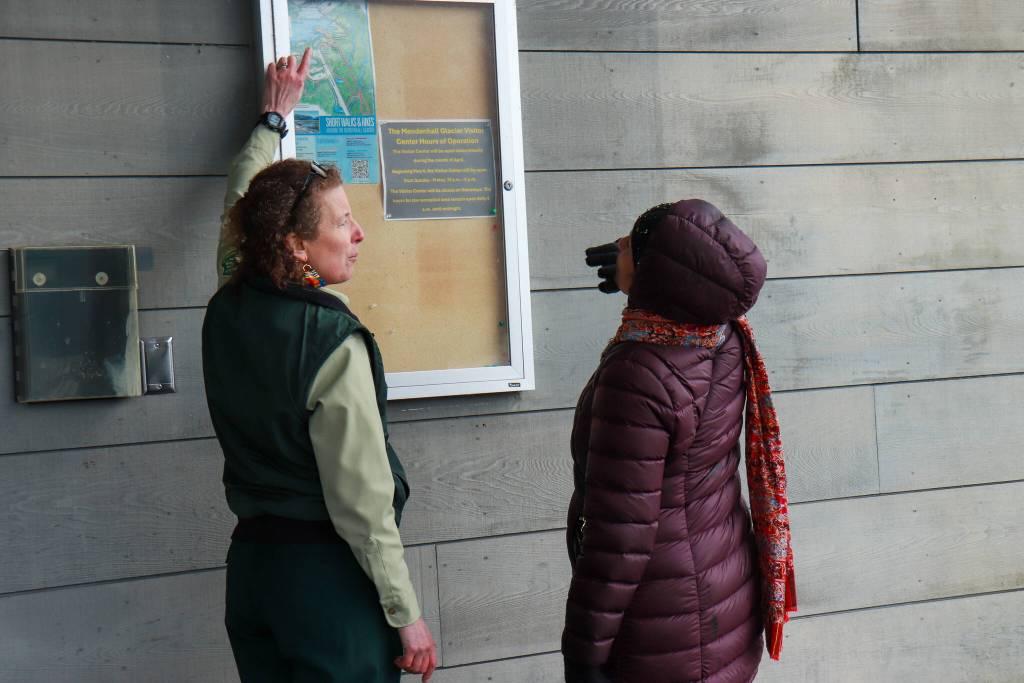 Juneau Deputy District Ranger Laura Buchheit shows a tourist the trails she can use at the Mendenhall Glacier Recreation Area on Monday, April 14, 2025. (Jasz Garrett / Juneau Empire)