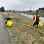 Regina Demmert and Casey Yakovich clean up trash in a median strip near Juneau International Airport on Saturday. (Mark Sabbatini / Juneau Empire)