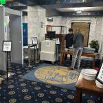 A visitor places items in a bin at the new security checkpoint at the Alaska State Capitol on Monday morning. (Mark Sabbatini / Juneau Empire)