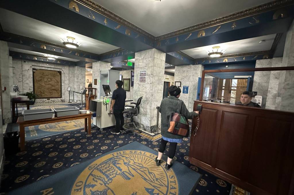 A worker at the Alaska State Capitol uses an access keychain fob to bypass the new security scanner at the Alaska State Capitol on Monday. (Mark Sabbatini / Juneau Empire)