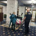 Lee Hart puts her jacket back on while talking with security officer Rayme Vinson after going through the new security screening process at the Alaska State Capitol on Monday morning. (Mark Sabbatini / Juneau Empire)