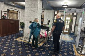 Lee Hart puts her jacket back on while talking with security officer Rayme Vinson after going through the new security screening process at the Alaska State Capitol on Monday morning. (Mark Sabbatini / Juneau Empire)