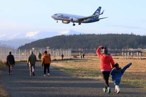 An Alaska Airlines plane passes above participants in the annual Turkey Trot run/walk next to Juneau International Airport on Thanksgiving Day of 2022. (Ben Hohenstatt / Juneau Empire file photo)