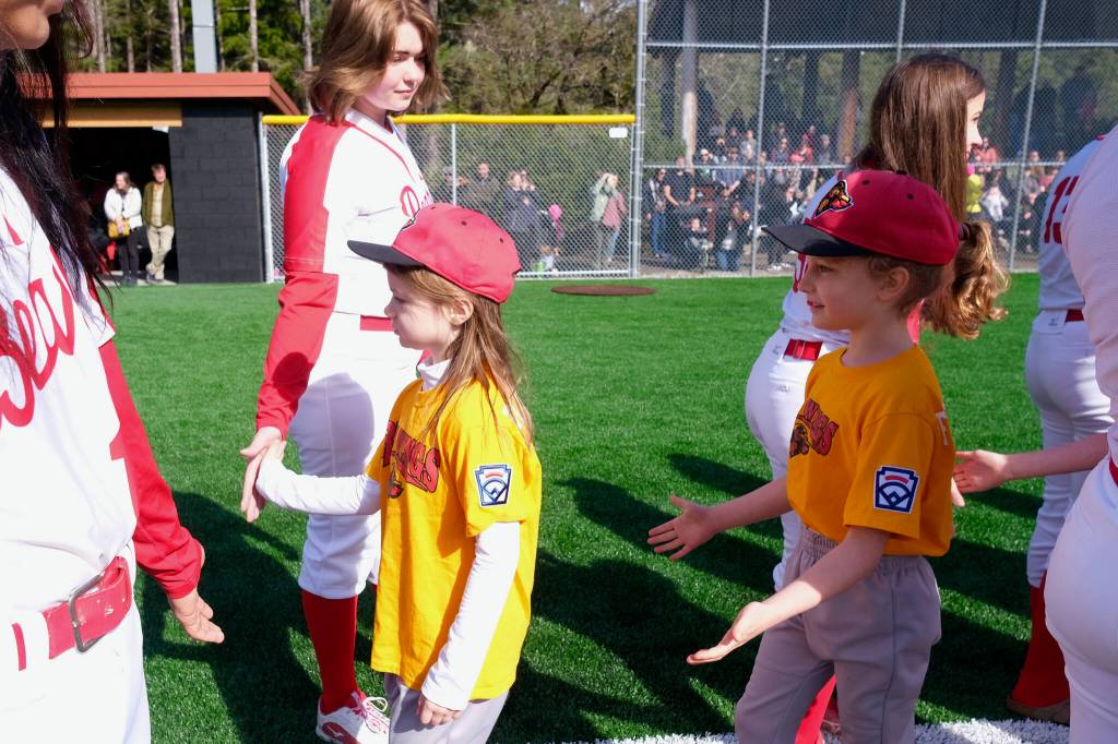 Gastineau Channel Little League youth players are welcomed onto the field by the Juneau-Douglas High School: Yadaa.at Kalé Crimson Bears softball team during Saturdays Opening Day, and field grand reopening and rededication at Adair Kennedy Memorial Park. (Klas Stolpe / Juneau Empire)