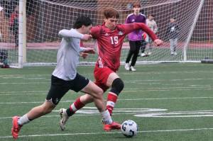 Juneau-Douglas High School: Yadaa.at Kalé senior defender Reed Maier (19) marks an attack by West Anchorage senior Noah Robinson during the Crimson Bears 1-1 tie with the Eagles on Friday at Adair Kennedy Memorial Park. (Klas Stolpe / Juneau Empire)