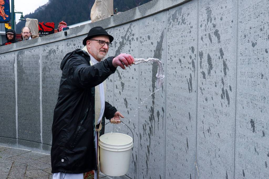 The Rev. Gordon Blue from the Church of the Holy Trinity blesses the engraved names of the Alaska Commercial Fishermens Memorial wall on Saturday, May 3, 2025. (Jasz Garrett / Juneau Empire)