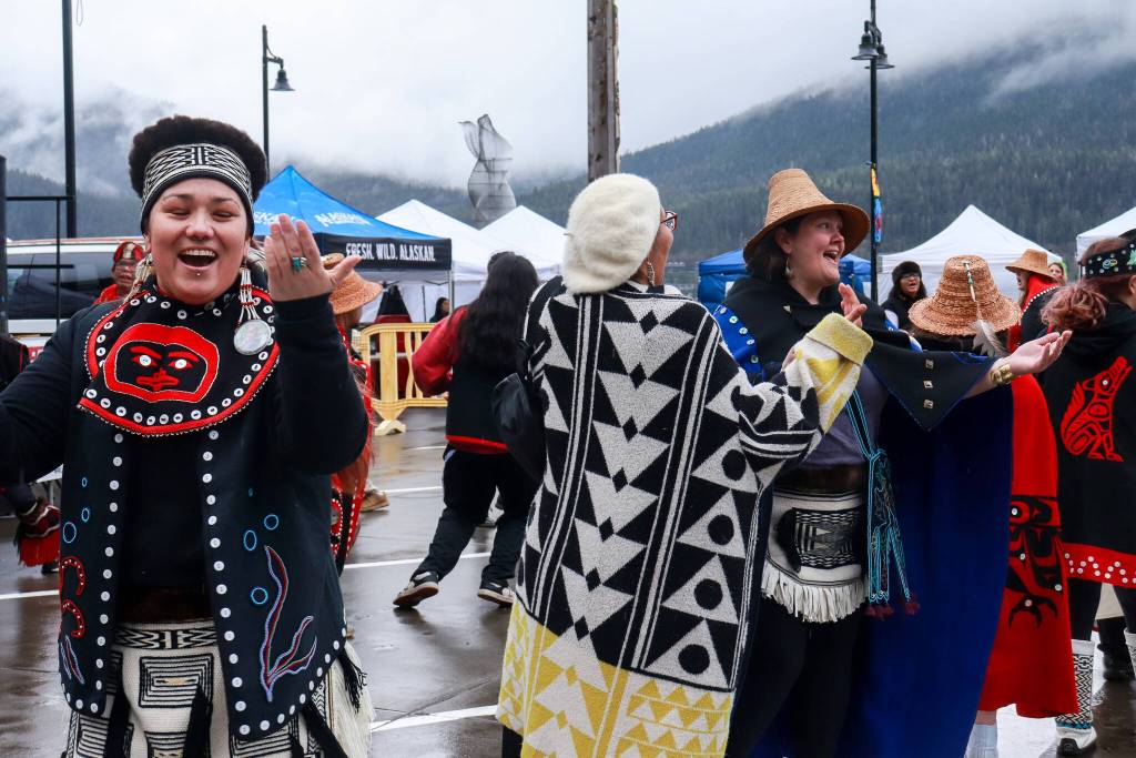 Donedin Jackson (center), who traveled from Alberta, Canada, is pulled from the audience into dance by her friend Davina Cole (left) at the Juneau Maritime Festival on Saturday, May 3, 2025. (Jasz Garrett / Juneau Empire)